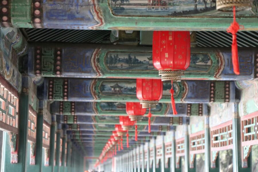Close-up of traditional red lanterns hanging in Beijing's Summer Palace with intricate ceiling artwork.