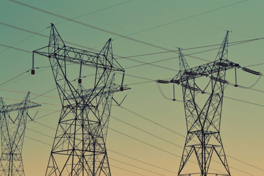 Silhouette of high voltage power lines against a twilight sky, illustrating energy infrastructure.