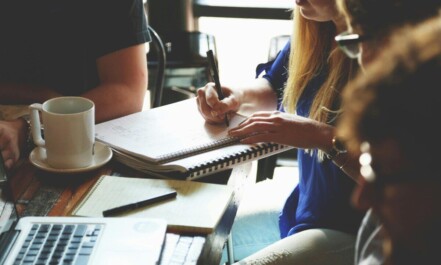 A group of young adults working together on a project at a casual meeting.