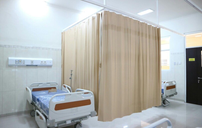 Quiet hospital ward with beds and privacy curtains in Surabaya, Indonesia.