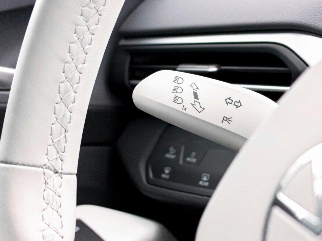 Detailed shot of car steering wheel and turn signal lever, showcasing modern vehicle interior design.
