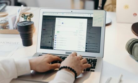 A person typing on a laptop in a bright, modern office setting, showing productivity and technology.