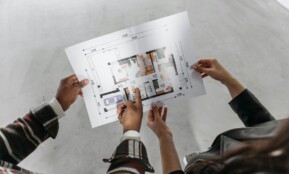 Two people reviewing architectural plans and measuring a new home design.