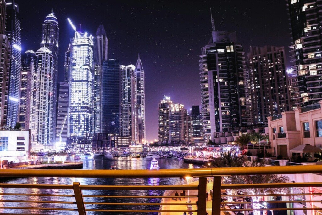 Vibrant night view of Dubai Marina with illuminated skyscrapers reflecting on the water.