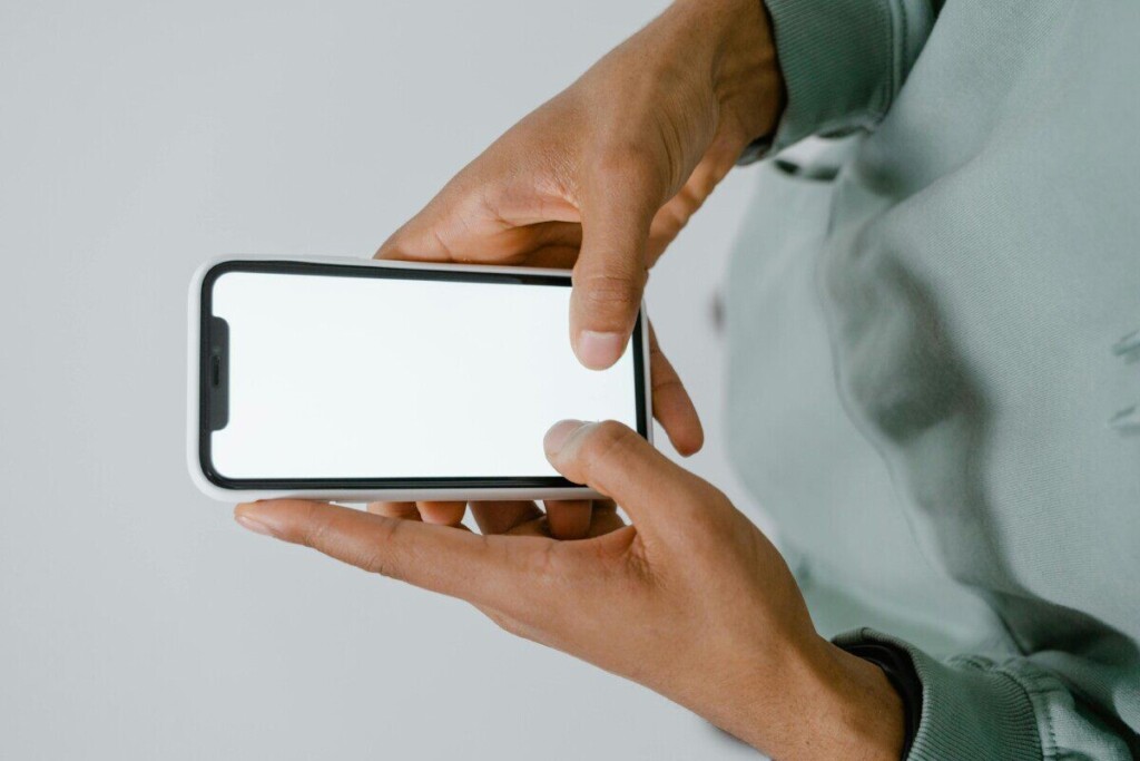 Hands holding a smartphone with a blank screen, perfect for mockups or copy space.