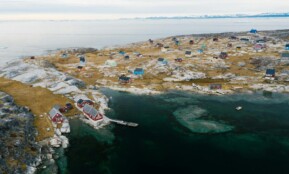 A beautiful aerial shot of a remote coastal village in winter, showcasing colorful houses and rocky landscape.