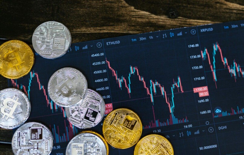 Close-up of gold and silver cryptocurrency coins on a digital trading chart.