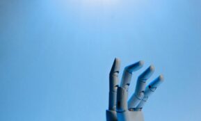 Robotic hand with articulated fingers reaching towards the sky on a blue background.