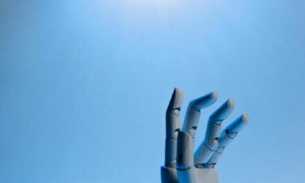 Robotic hand with articulated fingers reaching towards the sky on a blue background.