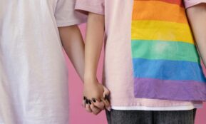 Close-up of two people holding hands, symbolizing love and LGBTQ+ pride.