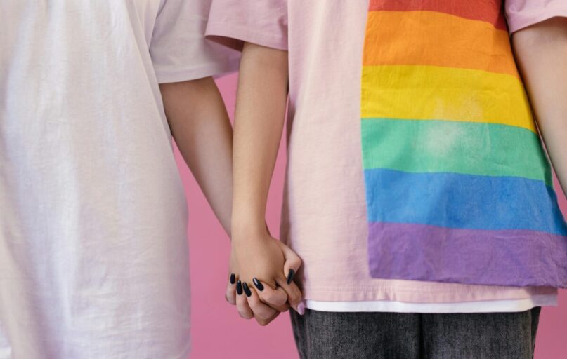 Close-up of two people holding hands, symbolizing love and LGBTQ+ pride.