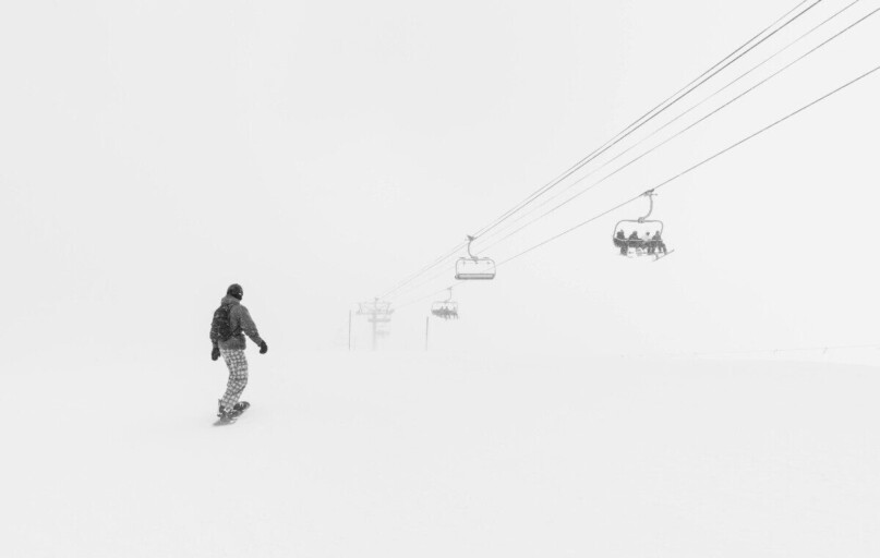 Snowboarder gliding under ski lifts in snowy Breckenridge, Colorado.