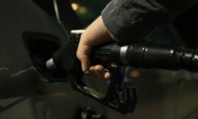 Close-up of a person refueling a car at a gas pump during night.