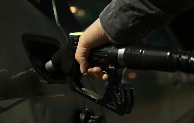 Close-up of a person refueling a car at a gas pump during night.