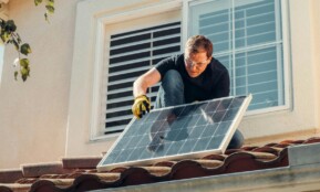 Solar technician installing a photovoltaic panel on a rooftop, promoting renewable energy.