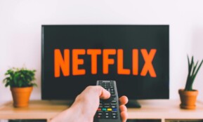 A hand holding a TV remote in front of a screen with Netflix, perfect for streaming and movie night themes.