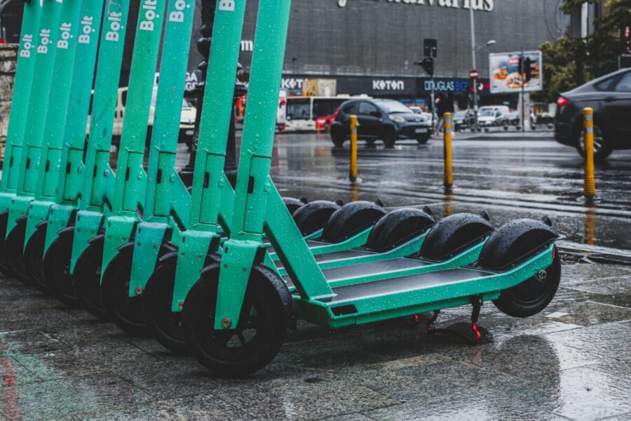 Rain-soaked electric scooters lined up on a city street, reflecting urban transportation.