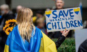 A peaceful protestor holds a 'Save Ukrainian Children' sign in New York City.