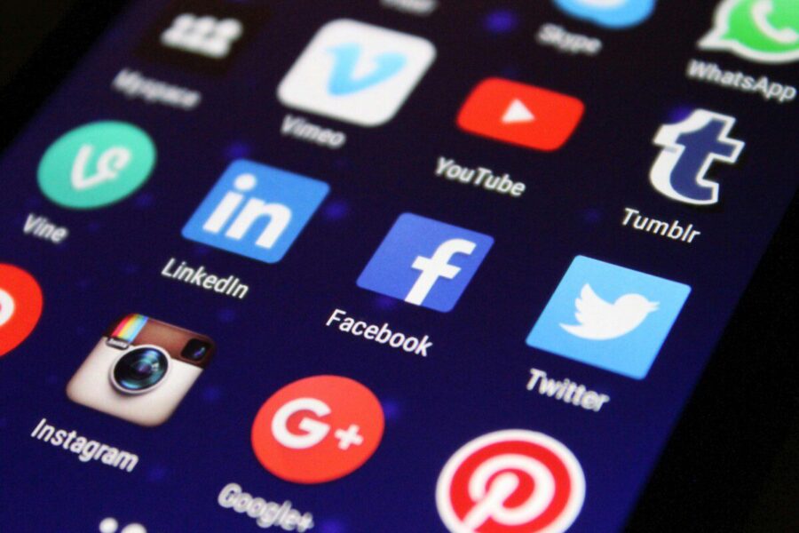 Close-up of a smartphone screen showing various social media app icons such as Facebook and Twitter.