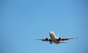 Virgin Australia aircraft captured mid-landing against a clear blue sky at Melbourne Airport.