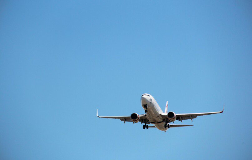 Virgin Australia aircraft captured mid-landing against a clear blue sky at Melbourne Airport.