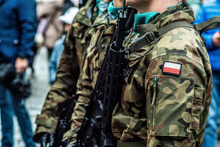 Close-up of Polish soldiers in camouflaged uniforms standing in line during a public event.