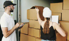 Two couriers organizing boxes in a delivery van, checking inventory.