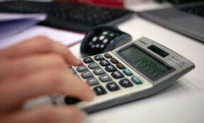 Close-up of a hand using a calculator on an office desk for accurate calculations.