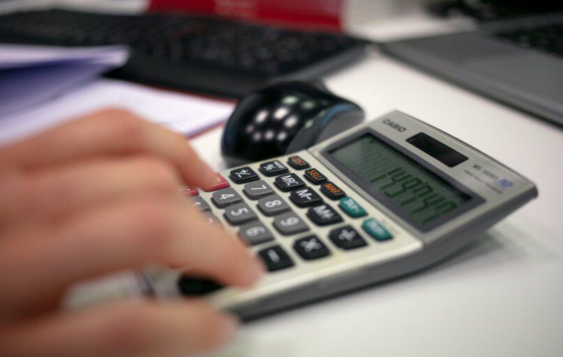 Close-up of a hand using a calculator on an office desk for accurate calculations.