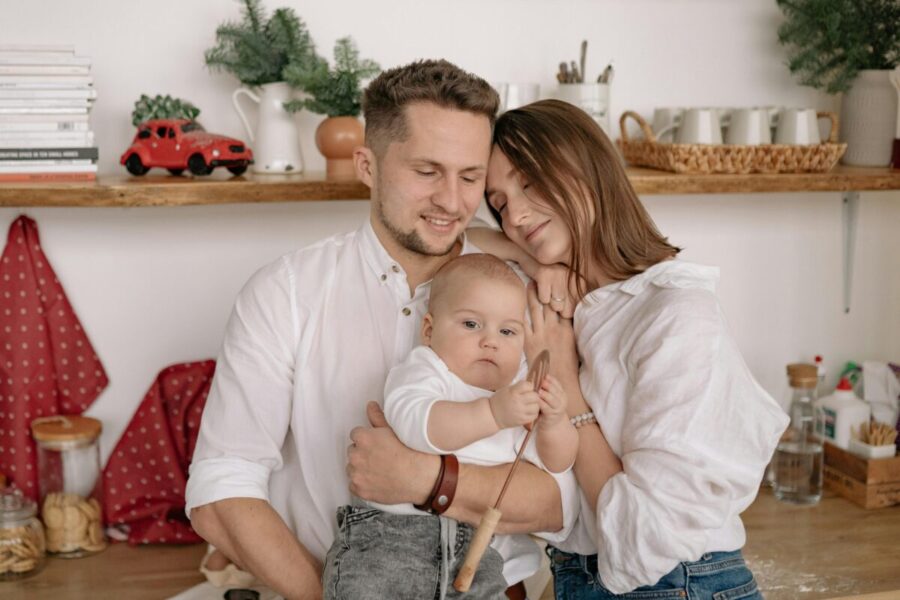 A joyful family of three embracing in a cozy kitchen. Warm and loving atmosphere.
