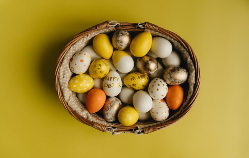 Basket of painted Easter eggs on yellow background. A festive springtime display.