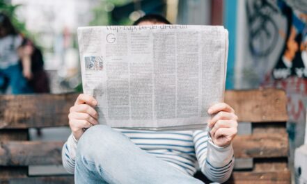 man sitting on bench reading newspaper