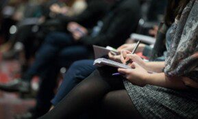 selective focus photography of people sitting on chairs while writing on notebooks