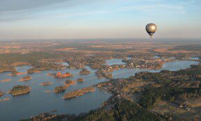 a hot air balloon flying over a large body of water