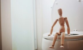 brown wooden doll on white ceramic toilet bowl