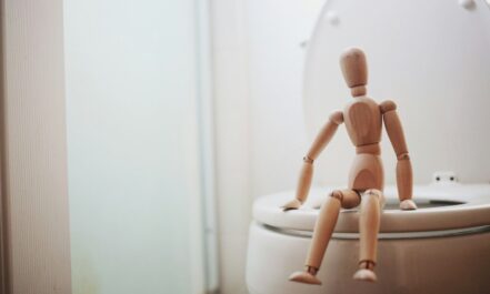 brown wooden doll on white ceramic toilet bowl