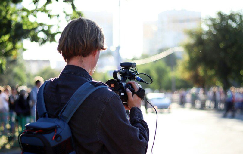 man in black jacket holding black dslr camera