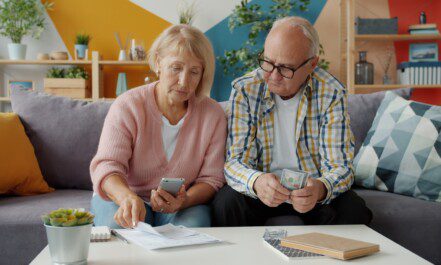 Elderly couple looking at bills and phone