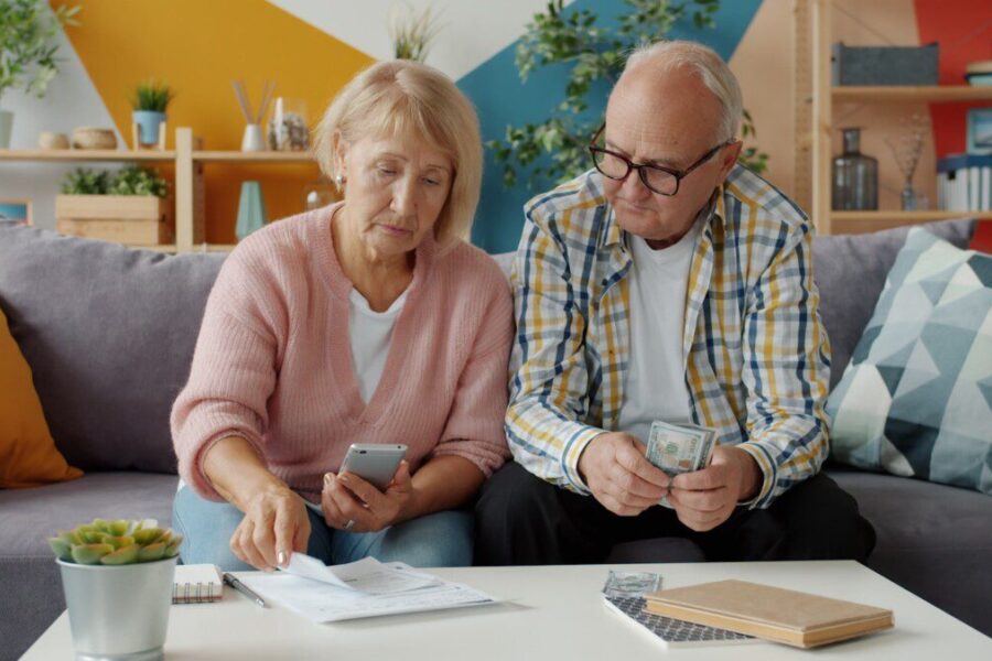 Elderly couple looking at bills and phone