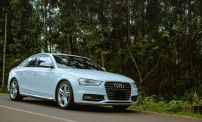 A white car is driving down the road