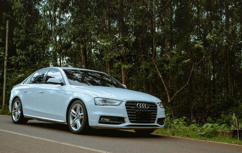 A white car is driving down the road