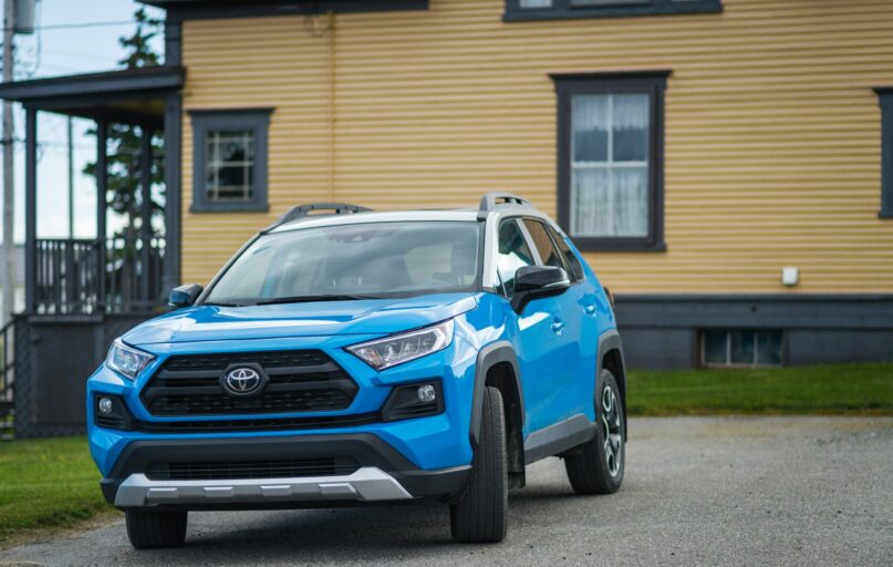 a blue toyota rav parked in front of a house