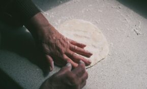 a person's hand on top of a pizza dough