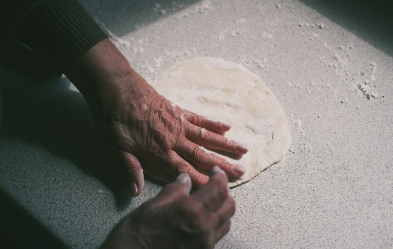 a person's hand on top of a pizza dough