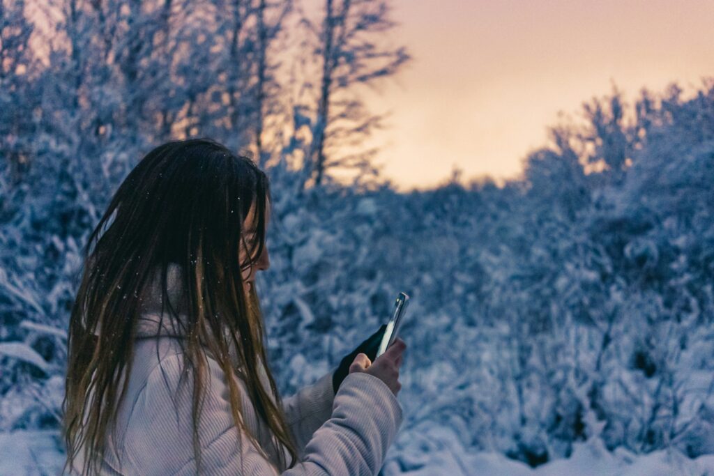 woman in white long sleeve shirt holding smartphone