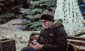 man using smartphone while sitting on bench