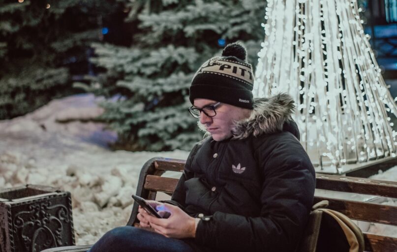 man using smartphone while sitting on bench