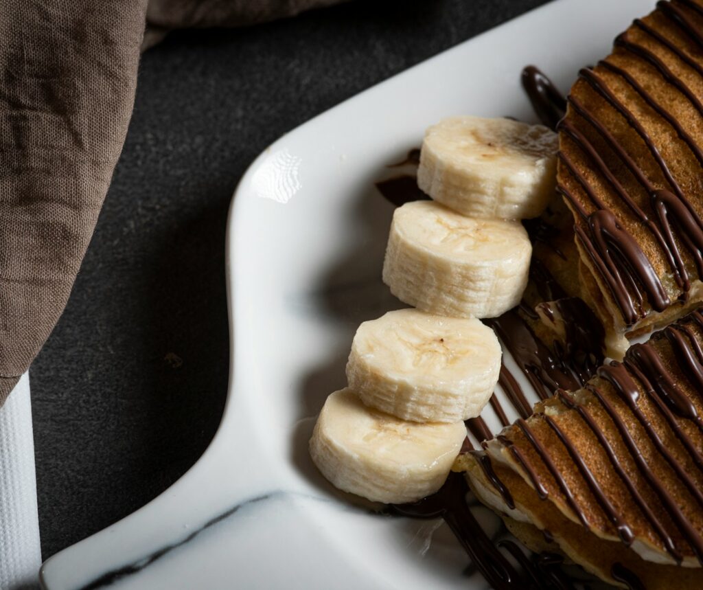 a white plate topped with banana slices and chocolate