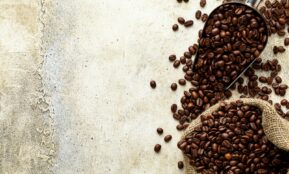 a scoop full of coffee beans next to a sack of coffee beans