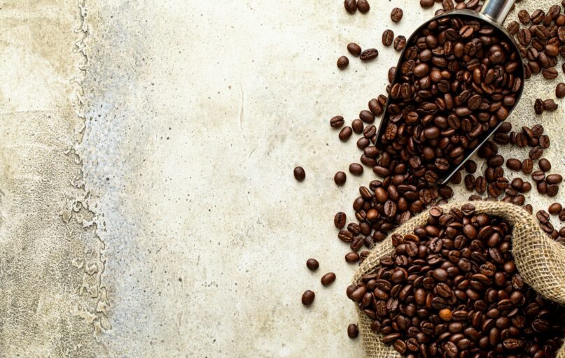 a scoop full of coffee beans next to a sack of coffee beans